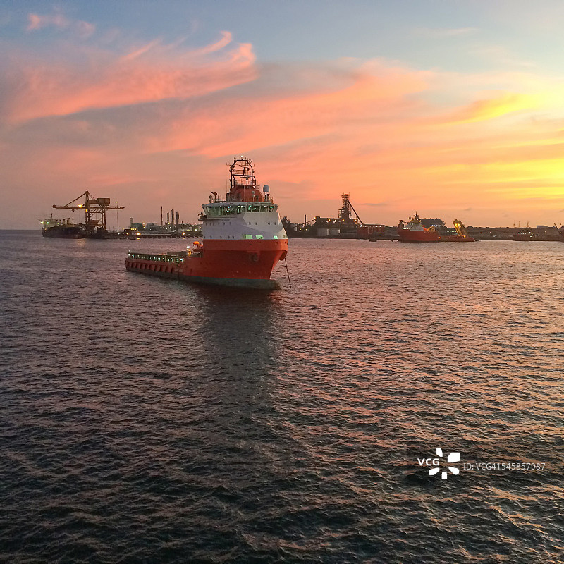 日落时停泊在港口码头的石油钻井平台供应船图片素材