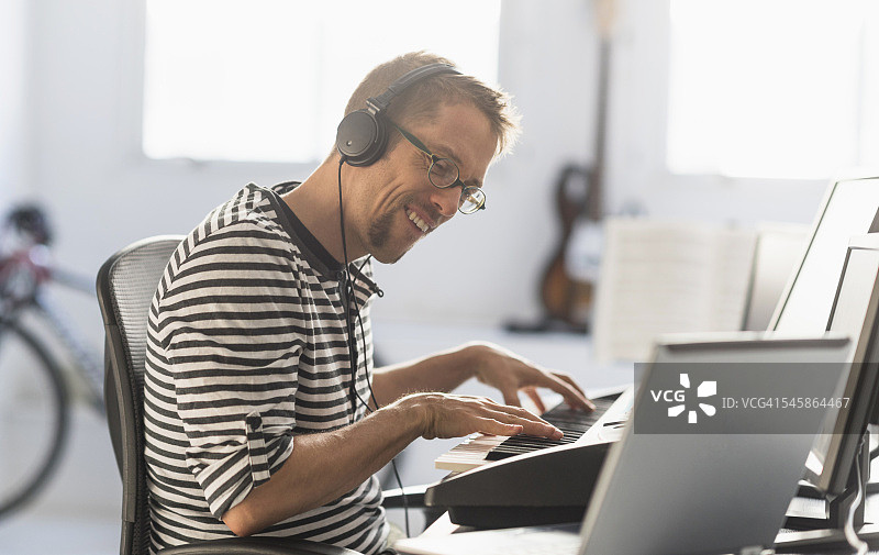 美国新泽西州：男人用笔记本电脑和合成器制作音乐图片素材