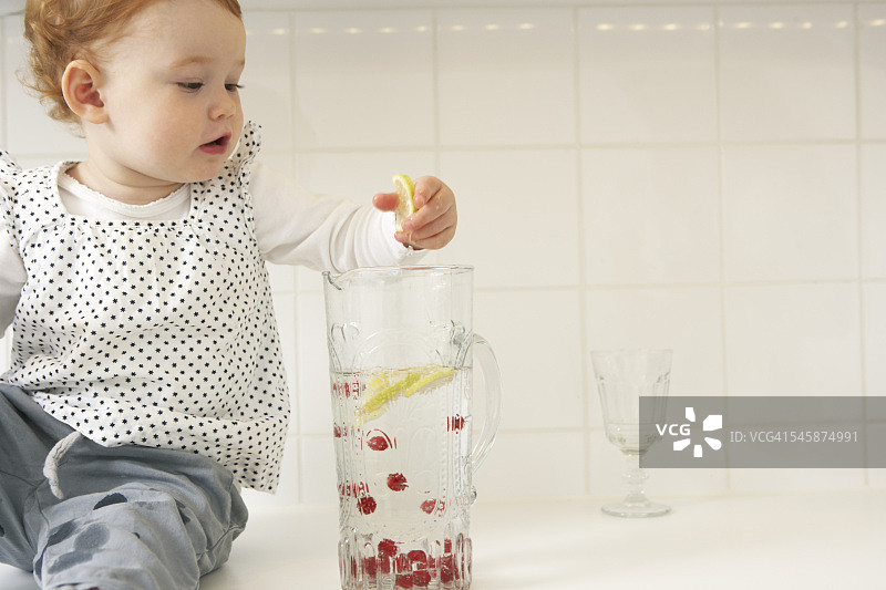 小女孩从水罐中取出柠檬片图片素材