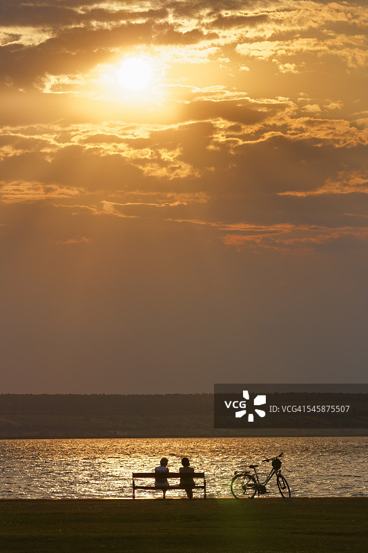 奥地利布尔根兰州伊尔米茨日落时坐在新锡德尔湖长椅上的人们图片素材