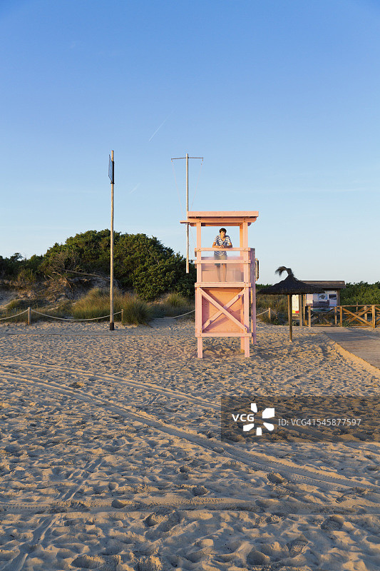 西班牙巴利阿里群岛马略卡岛，一名少年站在救生员台上图片素材