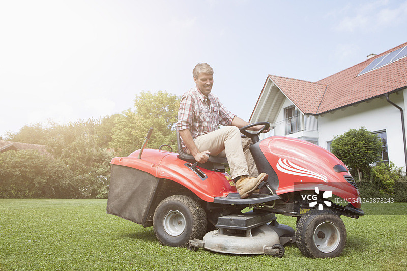 男子在花园里骑着割草机图片素材