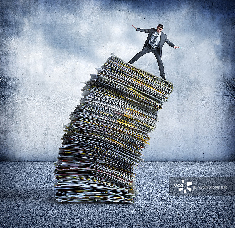 商务人士在高叠的文件堆上保持平衡图片素材