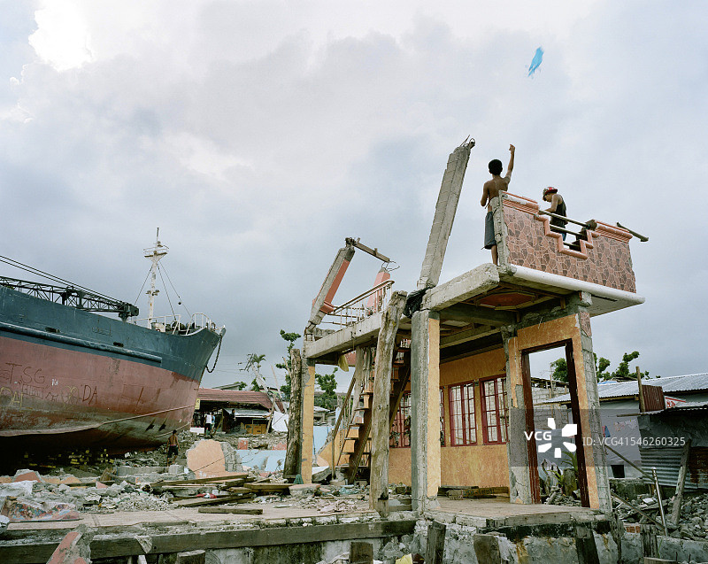 男孩在被摧毁的建筑物残骸上放风筝图片素材