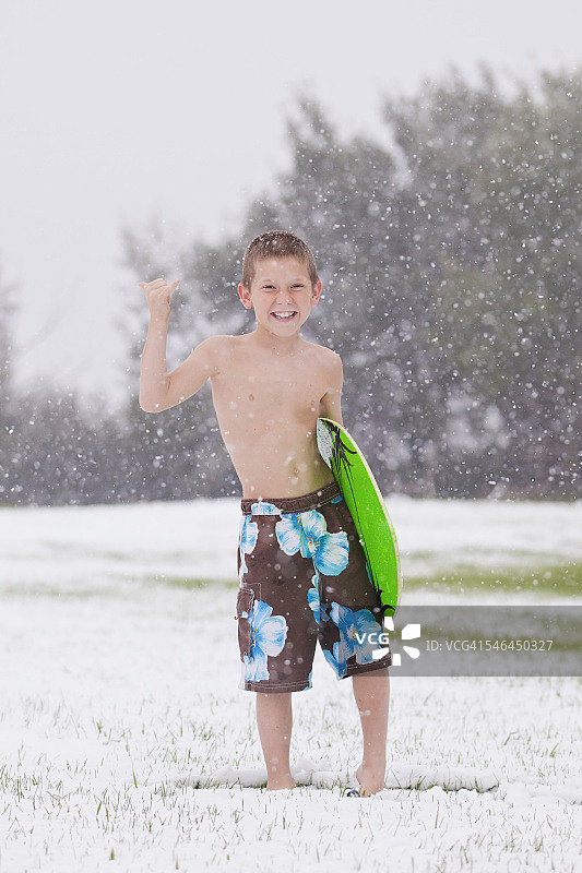男孩在雪地里抱着冲浪板图片素材