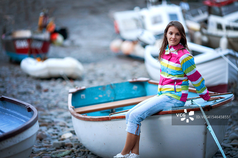 身穿条纹夹克，坐在船上的年轻女孩图片素材