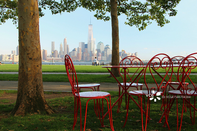 美国新泽西州霍博肯市，从A码头公园看到的下曼哈顿天际线，配有红色金属桌椅图片素材