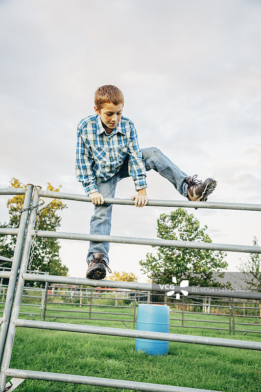 在农场攀爬栅栏的白人男孩图片素材