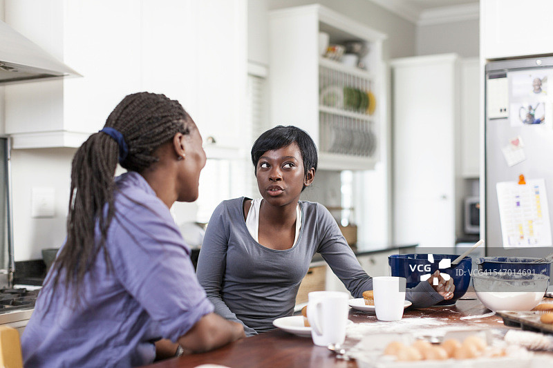 非洲裔母亲和十几岁的女儿在开普敦咖啡馆聊天吃纸杯蛋糕，南非图片素材