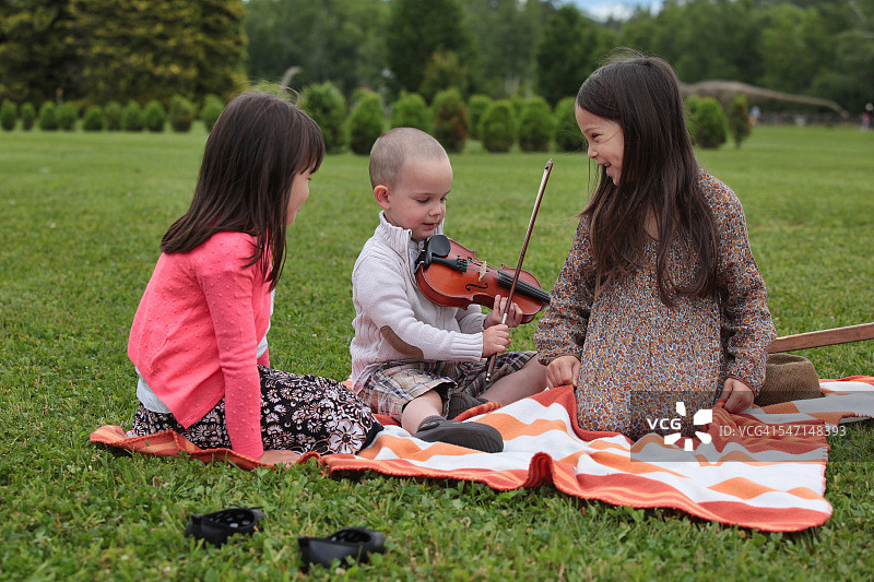女孩欣赏幼儿男孩的小提琴才华图片素材