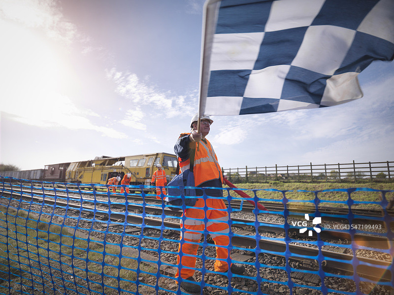 铁路维护工人在铁轨上挥舞旗帜图片素材