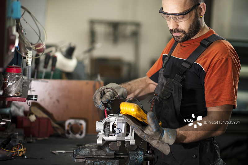 汽车修理工在车间用电压表检查电动机图片素材