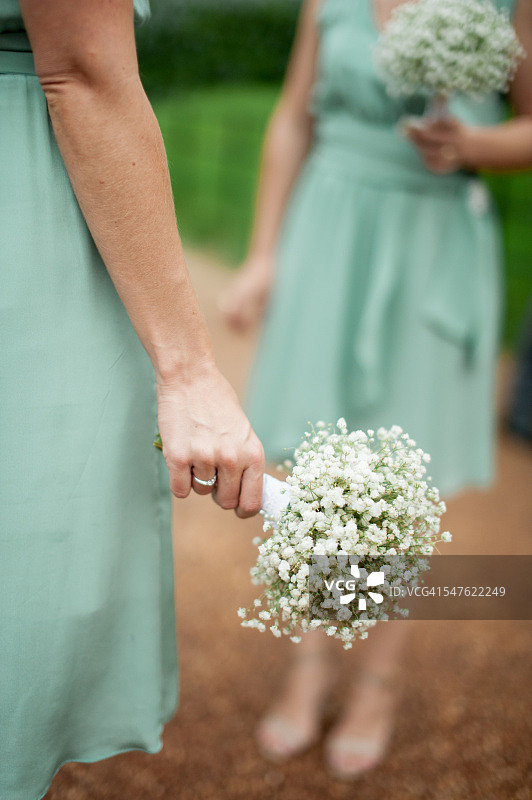 身穿绿色礼服、手捧满天星花束的伴娘图片素材