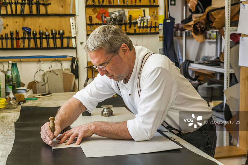 马鞍匠用模具切割皮革图片素材