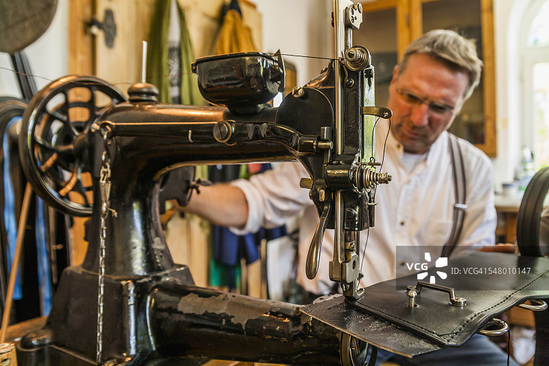 马鞍匠在皮革缝纫机上缝制跳马腰带图片素材