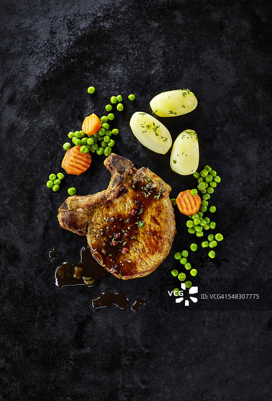 猪排搭配胡萝卜、豌豆和煮土豆图片素材