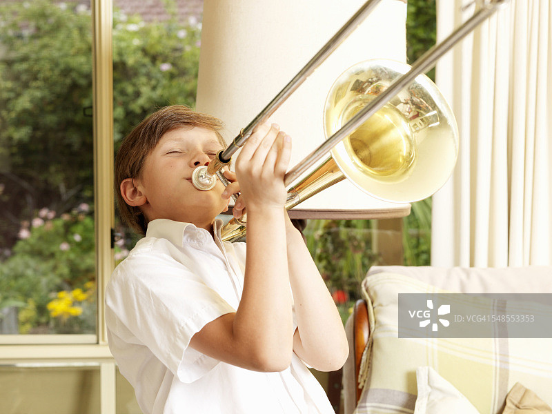男孩在客厅练习长号图片素材