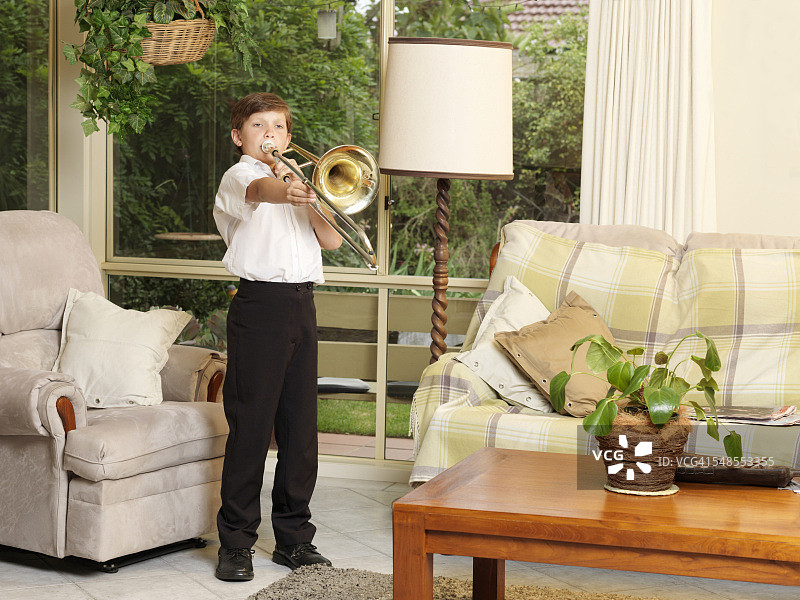 男孩在起居室里吹长号图片素材