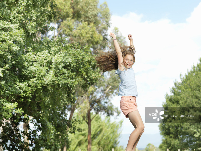 户外：少女张开双臂跳跃图片素材