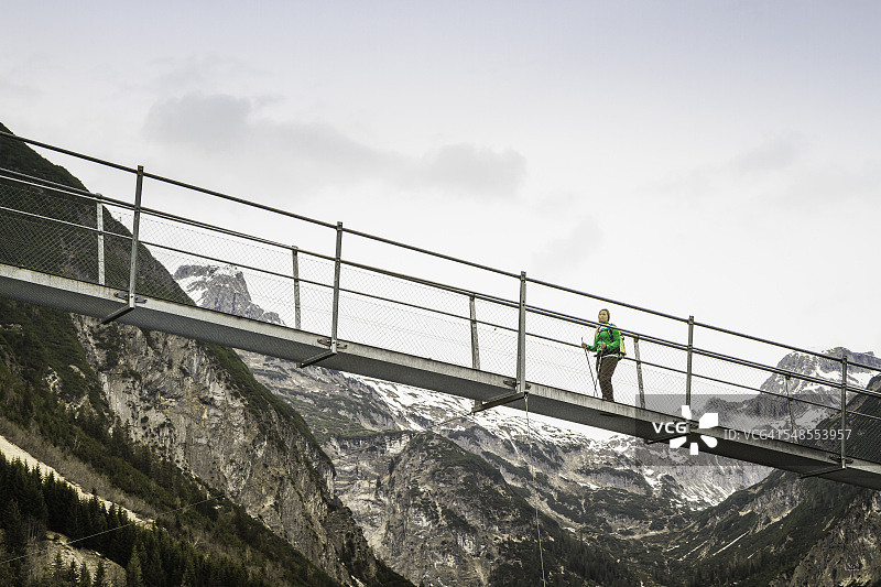 年轻女子在奥地利蒂罗尔州霍尔茨高的栈桥上徒步旅行的低角度景观图片素材