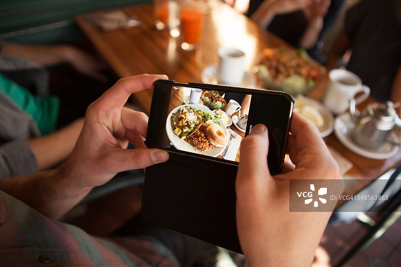 男人在素食餐厅拍摄食物照片的局部照片图片素材