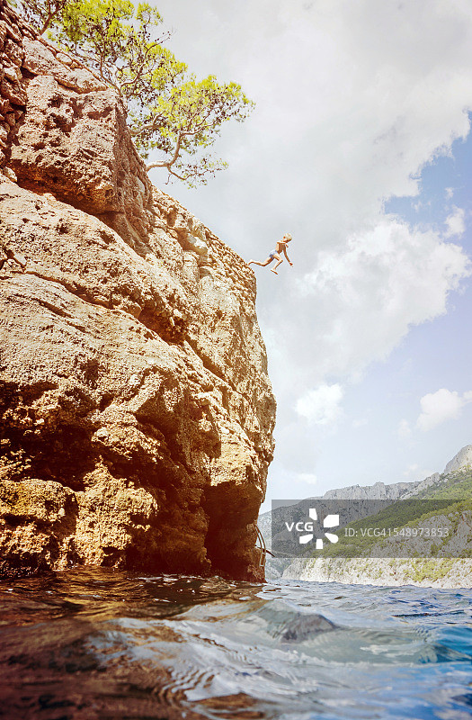 男孩从悬崖跳入水中图片素材