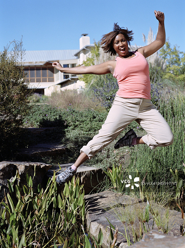 女子在温泉度假村花园里喜悦跳跃图片素材