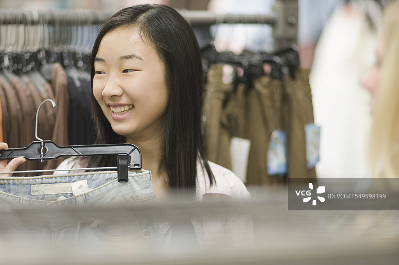 在商店里拿着牛仔裤的少女图片素材