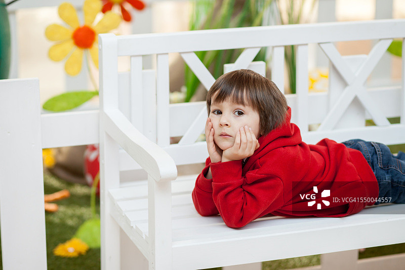 躺在长椅上的可爱男孩与复活节装饰图片素材