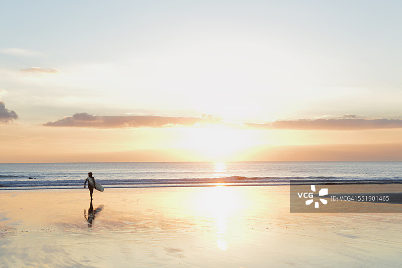 日落时走向大海的冲浪者图片素材
