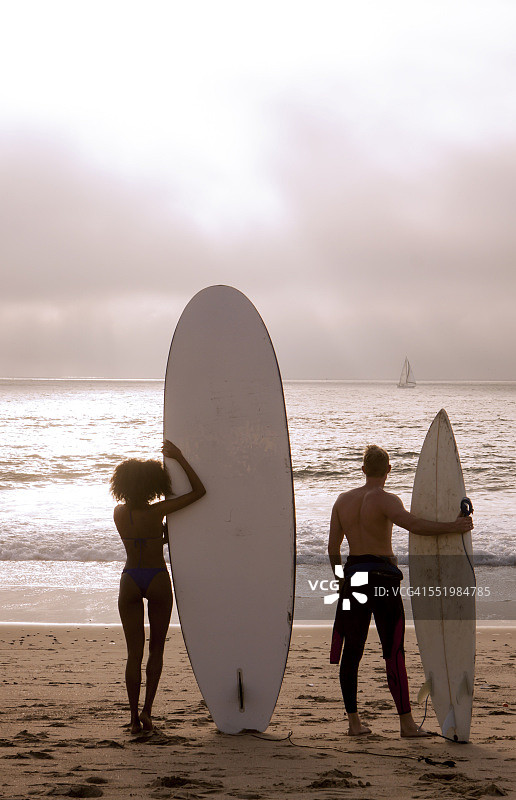 年轻冲浪情侣眺望大海的背影，美国加利福尼亚图片素材
