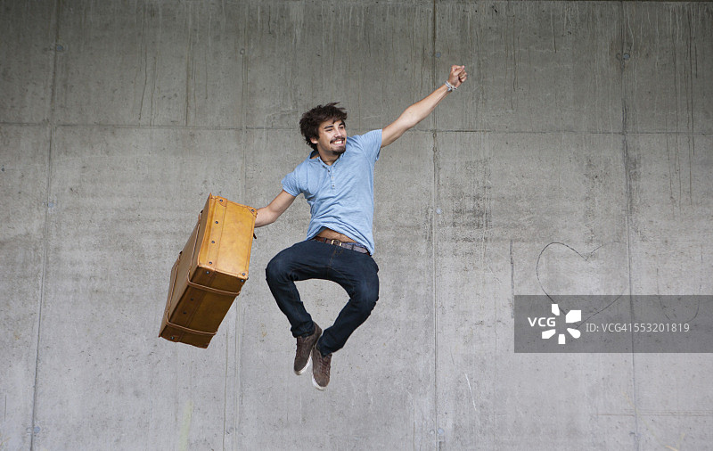 快乐的男人拿着皮箱跳跃图片素材
