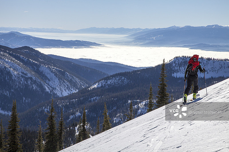 一名滑雪者穿越响尾蛇山脉，高耸于蒙大拿州比iterroot和米苏拉山谷的逆温层之上图片素材