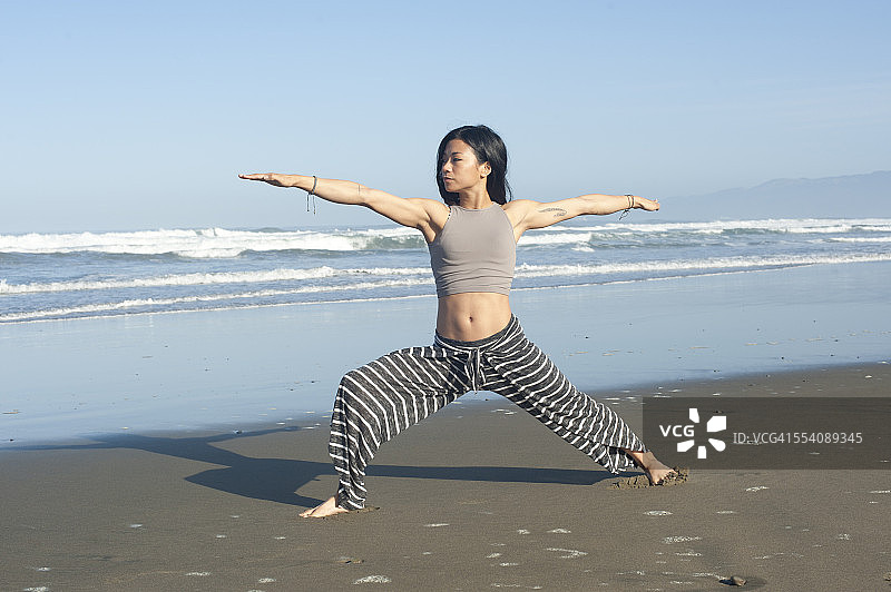 在海滩上做瑜伽的年轻女人图片素材