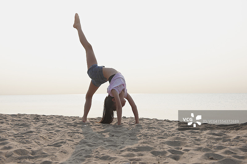 在海滩上做后弯的中国女孩图片素材
