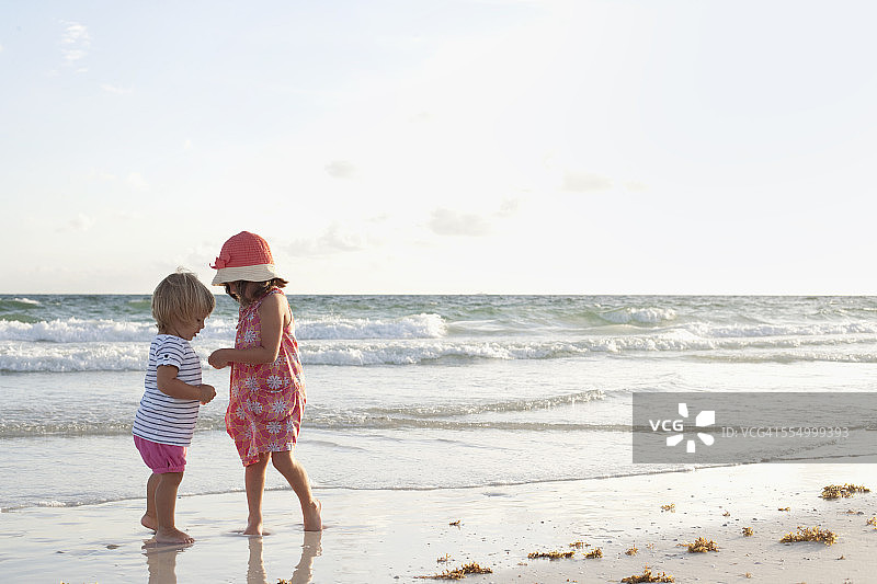 兄妹在日落时分的海滩上玩耍图片素材