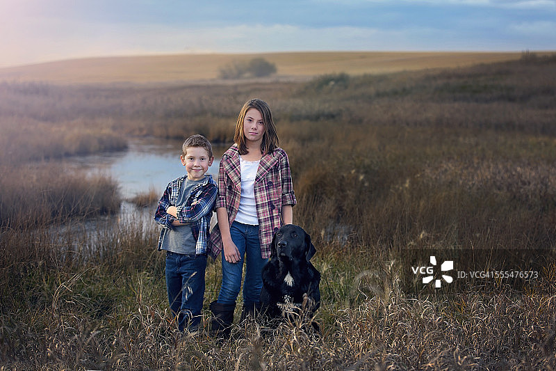 孩子们和他们的狗在小溪边图片素材