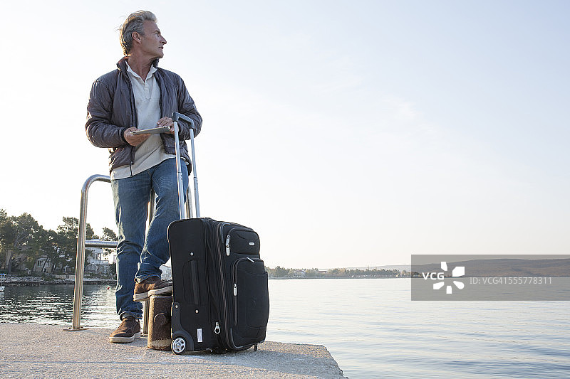 旅行者在渡轮码头等待，手持平板电脑图片素材