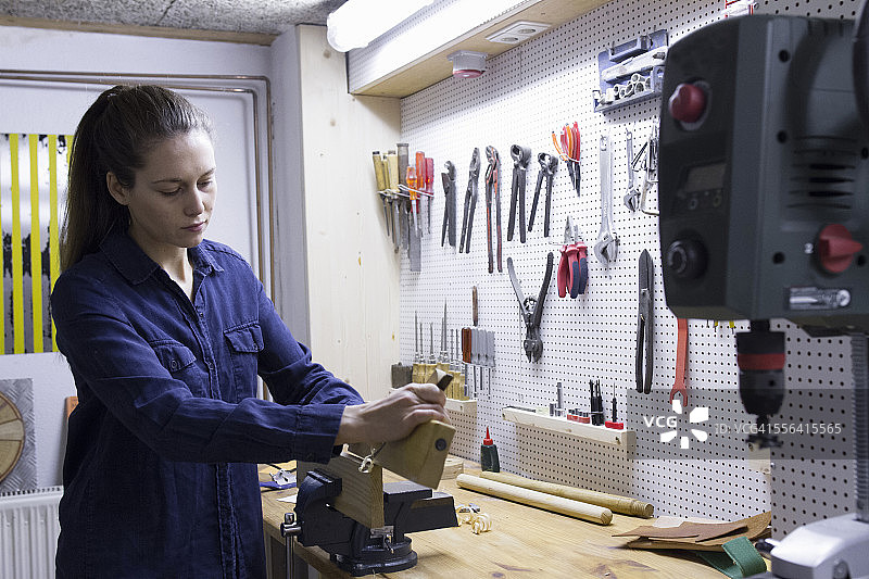 年轻女木匠在工作室虎钳中刨木材图片素材