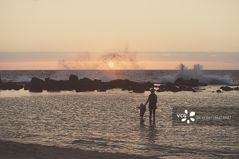 母亲和女童在海中划水，眺望海浪的剪影，夏威夷科纳，美国图片素材
