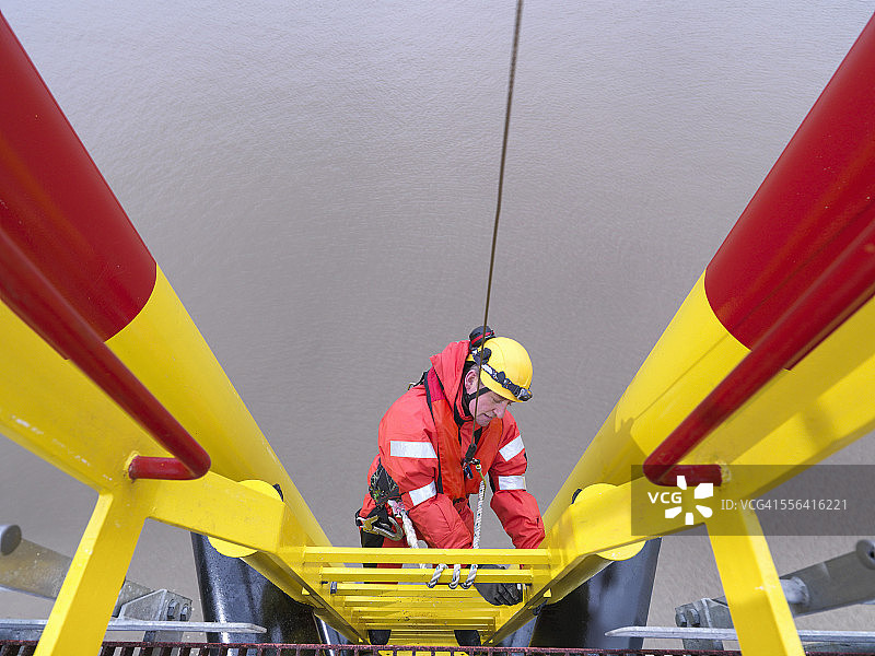 高角度拍摄：海上风电场工人攀爬涡轮机图片素材