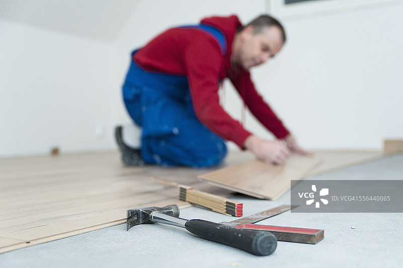 男人躺在复合地板上，前景是工具图片素材