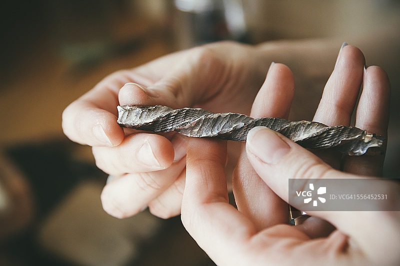 金匠以木纹金风格制作结婚戒指，手持扭曲的原材料图片素材