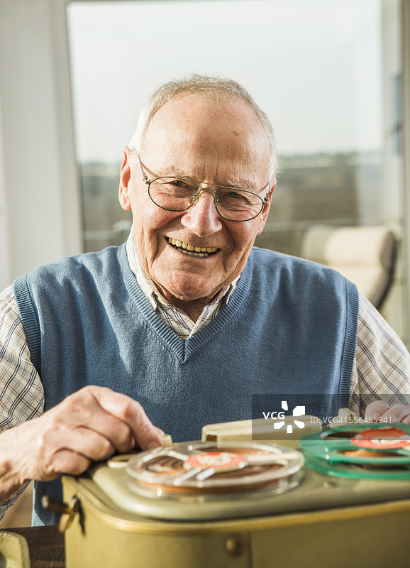面带微笑、操作老式录音机的年长男人图片素材