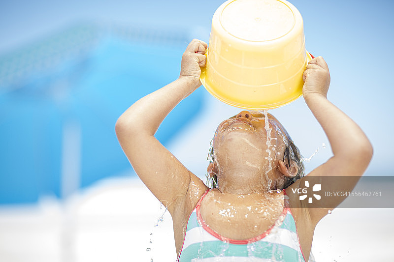 在海滩上用水桶泼水的女孩图片素材