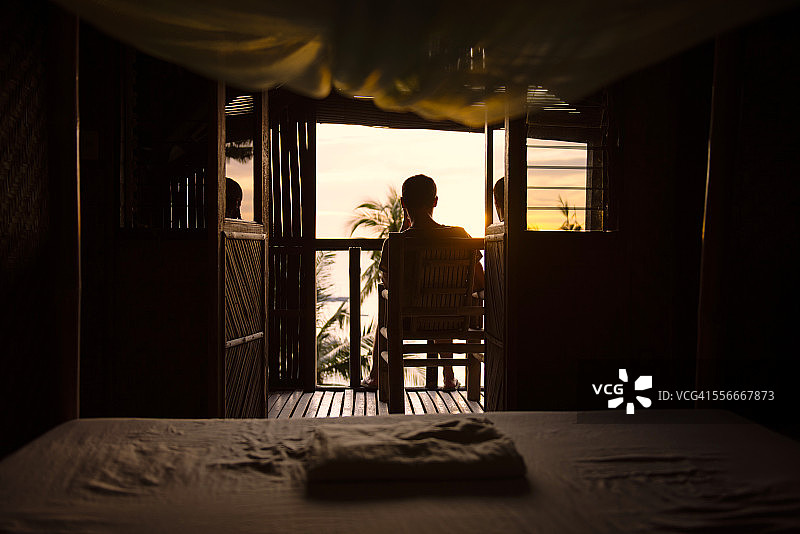 菲律宾阿波岛，男人在木屋的露台上欣赏日落图片素材