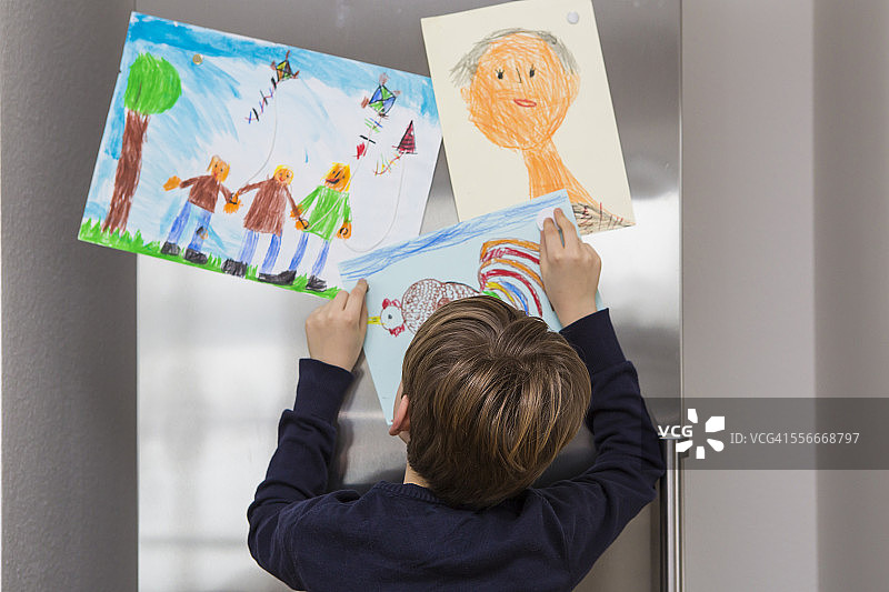 男孩把画贴在冰箱上图片素材