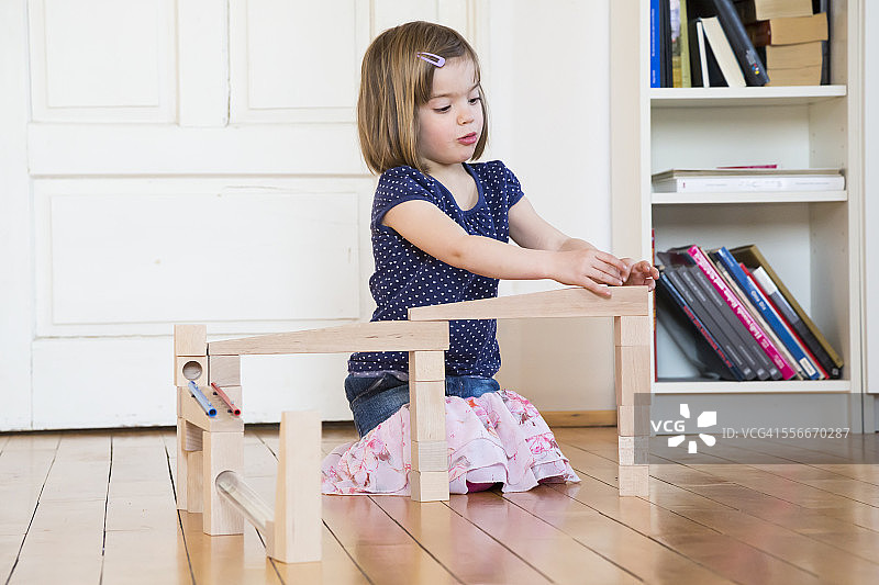 小女孩蹲在地板上玩弹珠图片素材