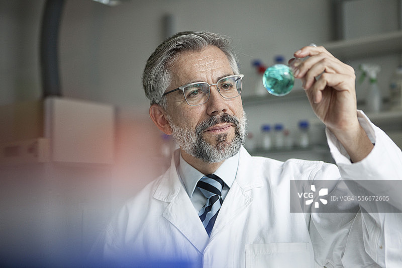 科学家在实验室检查圆底烧瓶中的液体图片素材