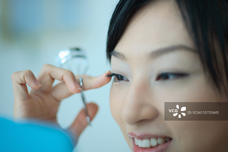 使用睫毛夹的年轻女人，特写图片素材